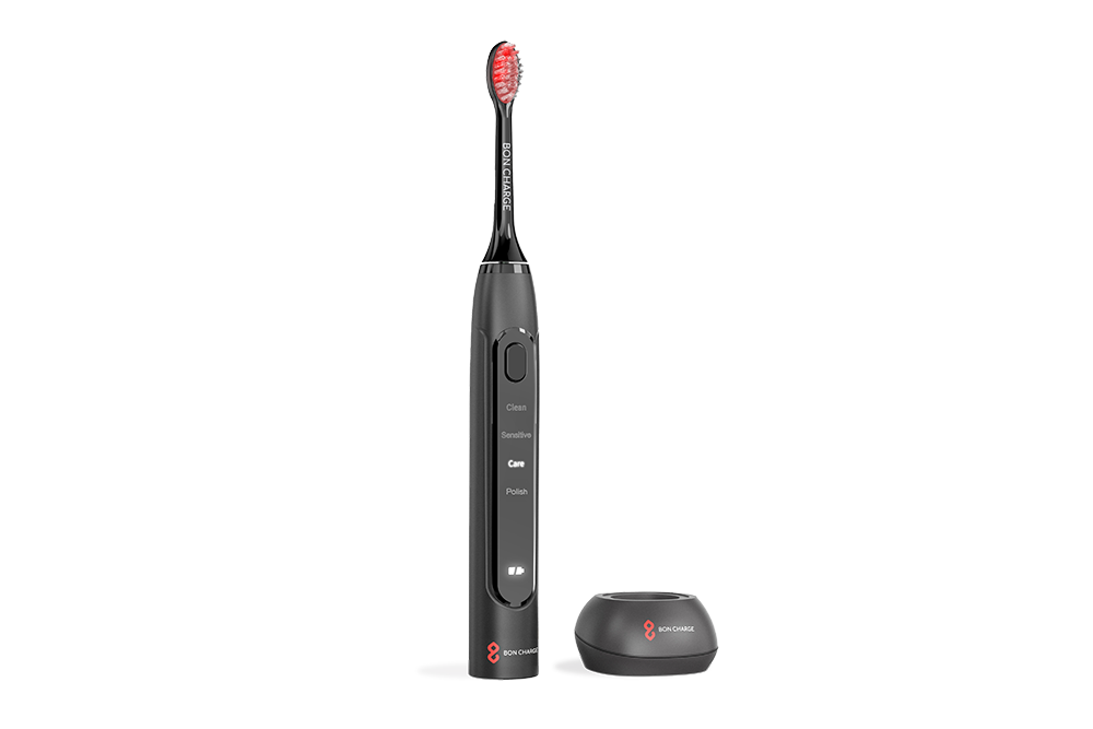 Black electric toothbrush with red bristle heads angled to the side